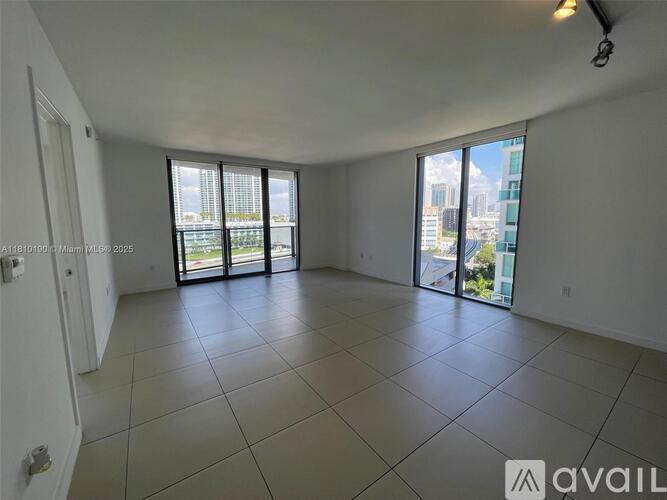 A spacious room with tiled flooring and sliding glass doors leading to a balcony.