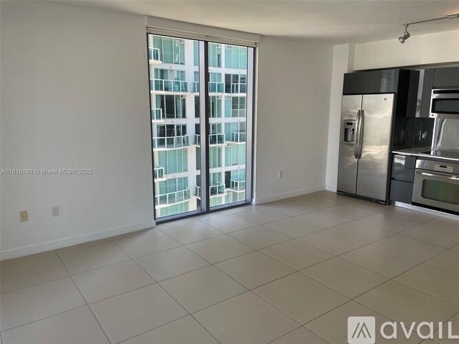 A spacious kitchen with a view of a high-rise building outside the window.