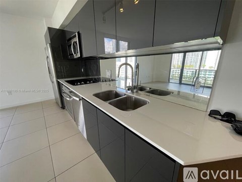 A modern kitchen with a stainless steel dishwasher and a double sink.