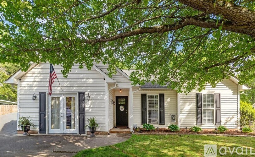A white house with a black door and a flag on the front porch.