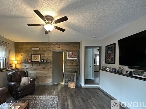A living room with a black leather couch and a wooden wall.