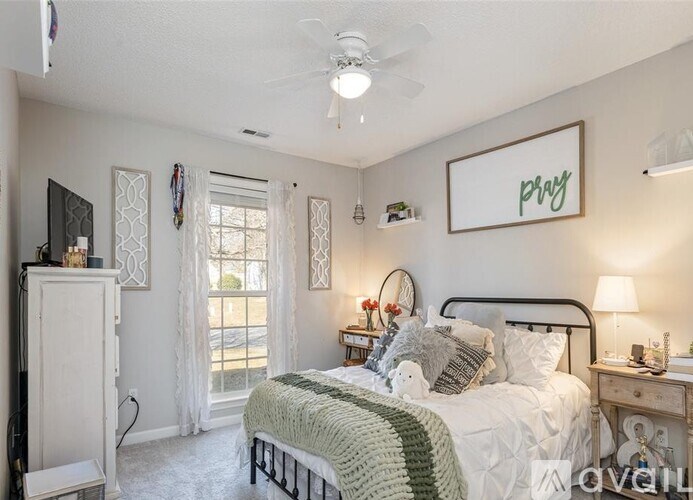 A bedroom with a bed, nightstand, and a window with curtains.