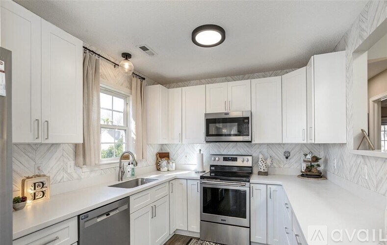 A kitchen with white cabinets and a marble backsplash.