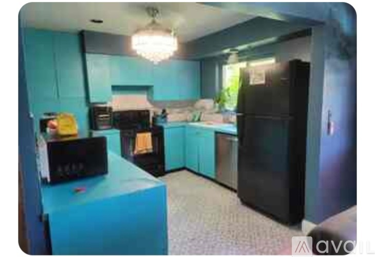A kitchen with a black refrigerator and a blue island.