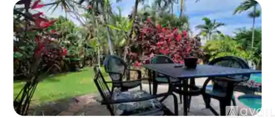 A table with chairs is set up outside with a pool in the background.