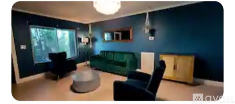 A living room with a green couch and a grey ottoman.