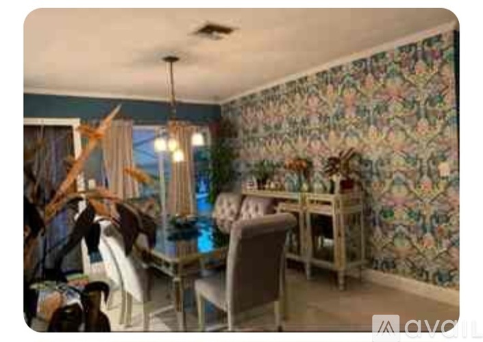 A dining room with a floral wallpaper and a table set for a meal.