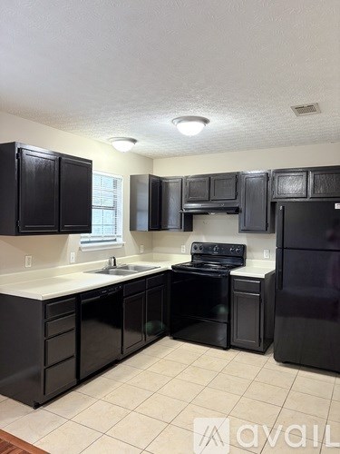 A kitchen with black cabinets and appliances.