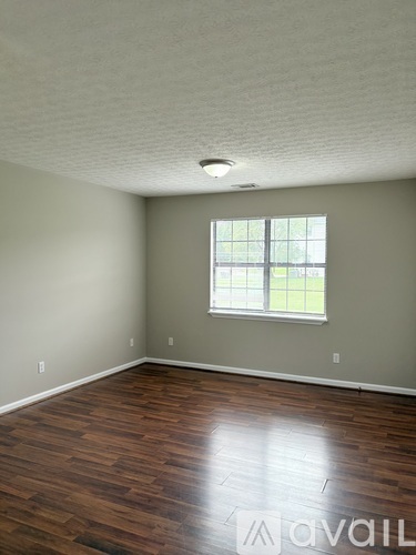 A room with wooden flooring and a window.