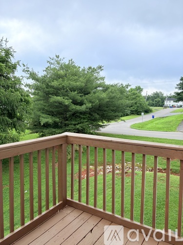 A wooden deck overlooks a grassy area with trees and a road in the distance.