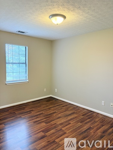 A room with wooden flooring and a window with blinds.