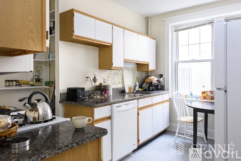 A kitchen with white cabinets and a black countertop.