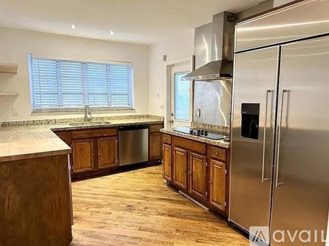A kitchen with wooden cabinets and a stainless steel refrigerator.