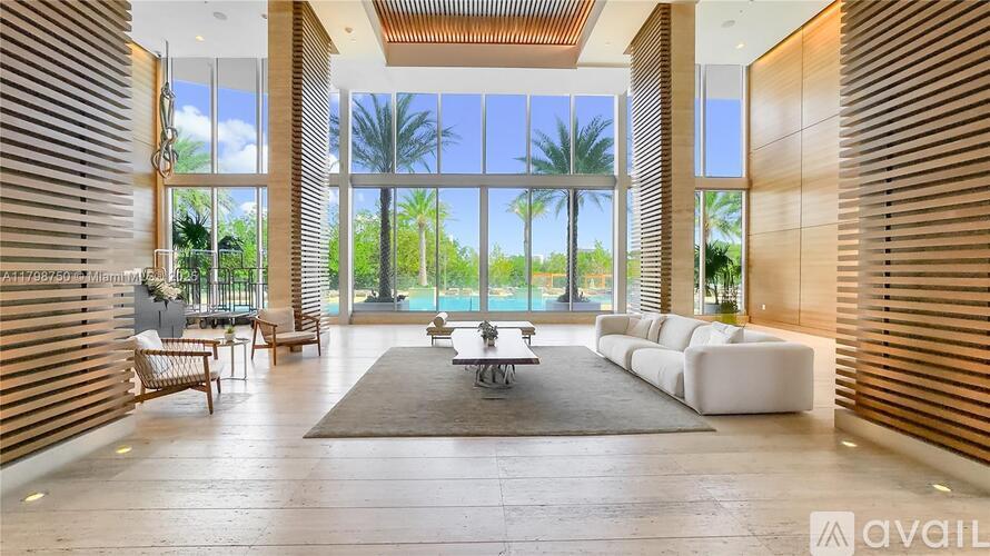 A spacious living room with a view of the outdoors through large windows.