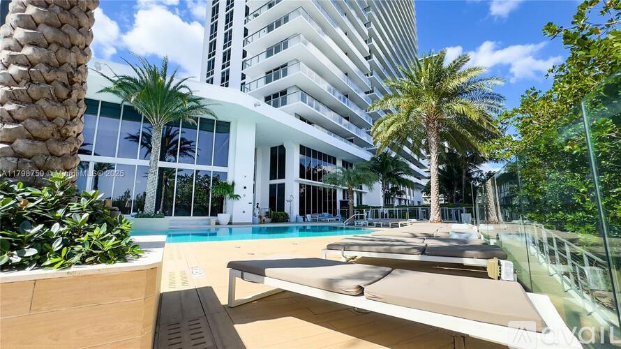 A pool area with a palm tree and a building in the background.