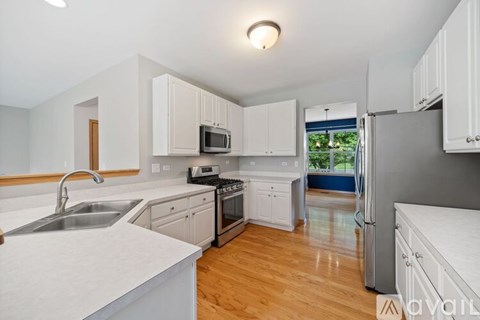 A kitchen with white cabinets and a wooden floor.