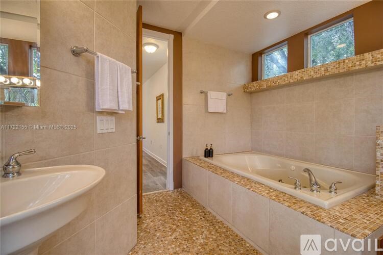 A bathroom with a tub, sink, and mirror.