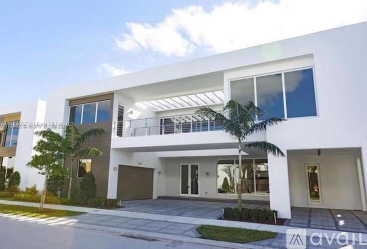 A modern white house with a balcony and a driveway.