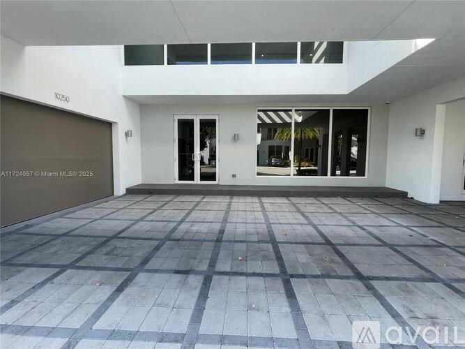A large, empty room with a tiled floor and a glass door leading to a balcony.