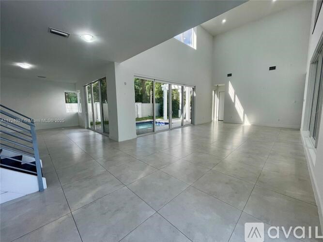 A spacious room with tiled flooring and large windows.