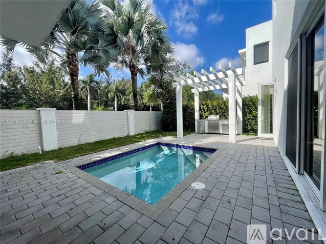 A pool surrounded by a white fence and a white pergola.