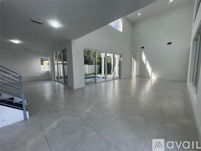 A spacious room with a tiled floor and large windows.