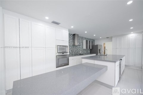 A modern kitchen with white cabinets and a grey countertop.