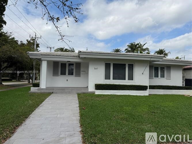 A white house with a grey roof and a green lawn in front.