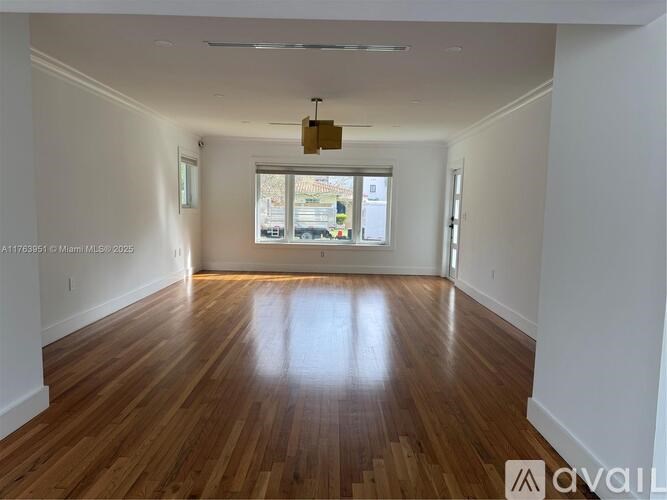 A spacious room with wooden flooring and a window.