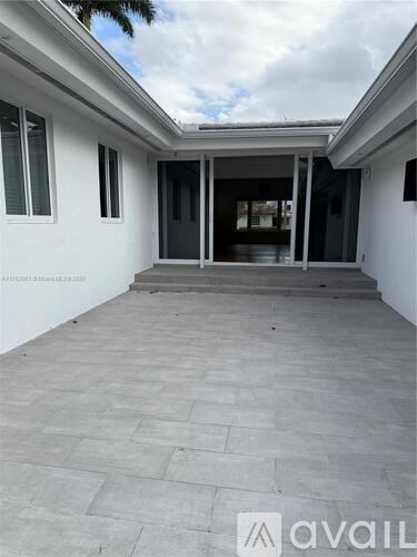 A spacious outdoor area with a tiled floor and a white wall.