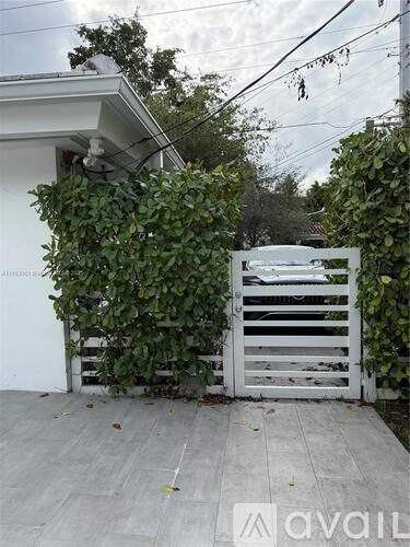 A white gate is blocked by a large green plant.
