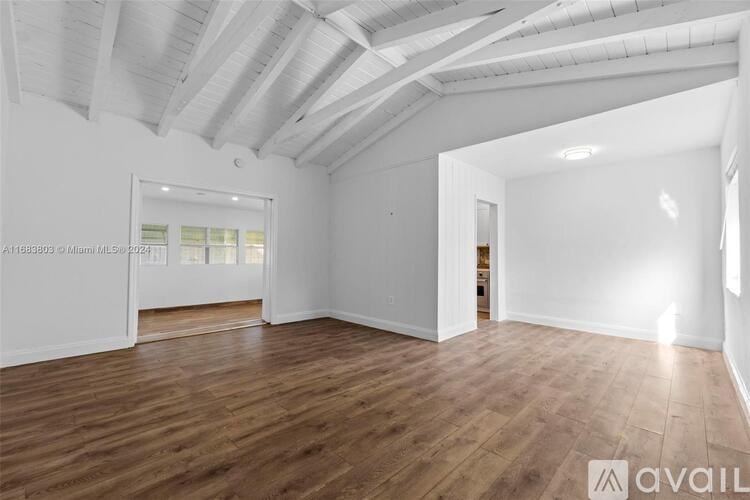 A spacious room with wooden flooring and white walls.