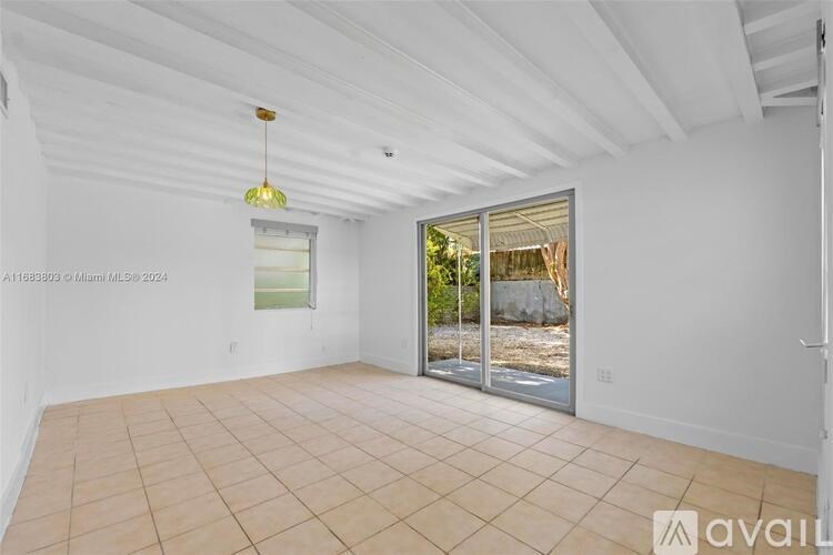 A large, empty room with a sliding glass door leading outside.