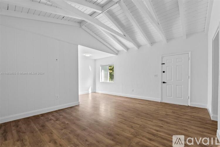 A spacious room with wooden floors and white walls.