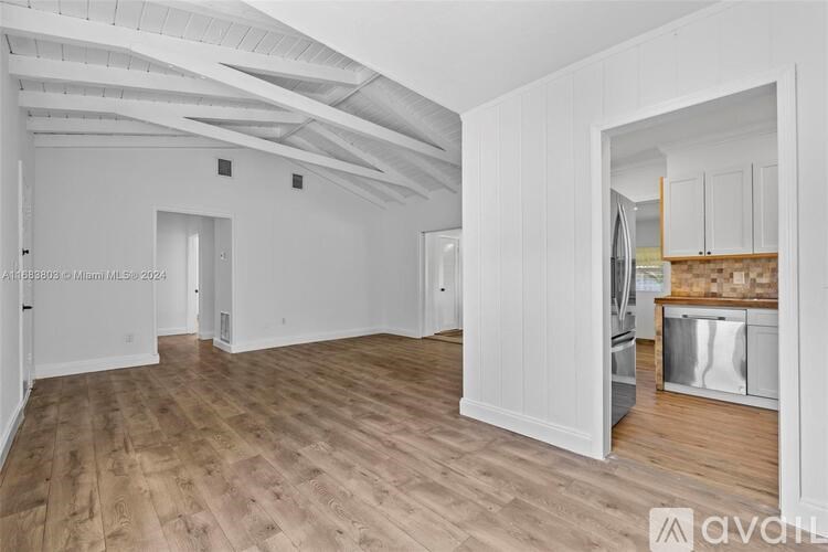 A spacious room with wooden flooring and white walls.