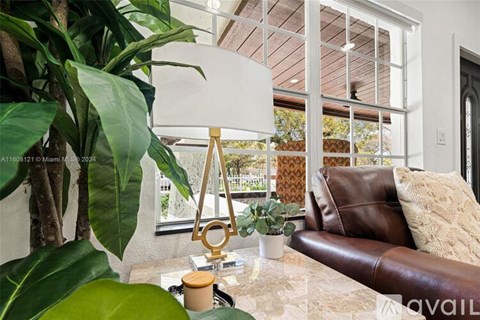 A living room with a brown leather couch and a large plant.