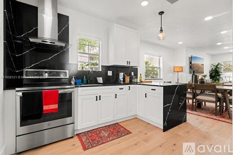 A modern kitchen with a black marble island and stainless steel appliances.