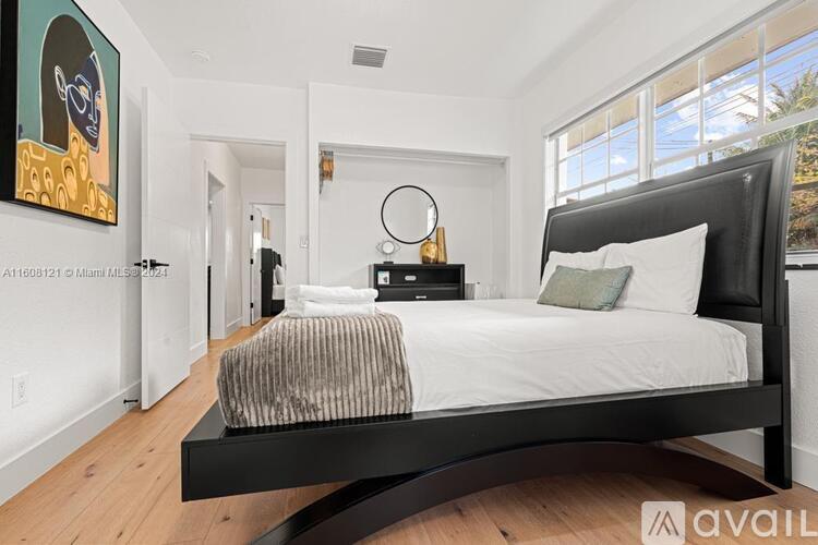 A bedroom with a large bed and a painting on the wall.