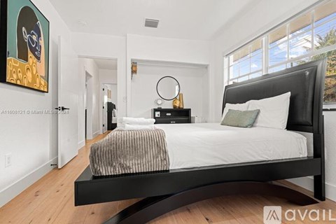 A bedroom with a large bed and a painting on the wall.