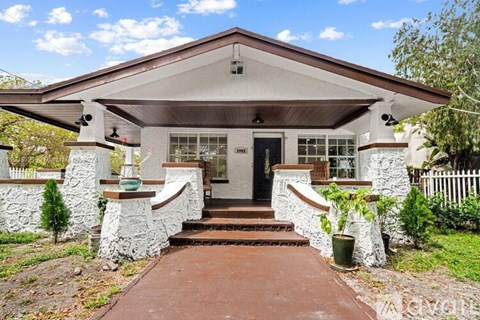 A house with a front porch and a red walkway leading to the front door.