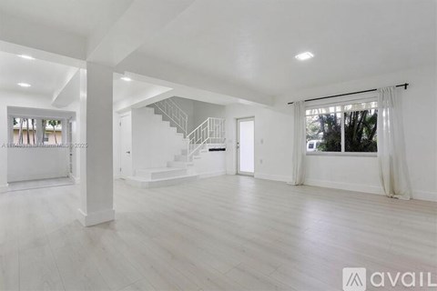 A spacious living room with a staircase leading to the upper floor.