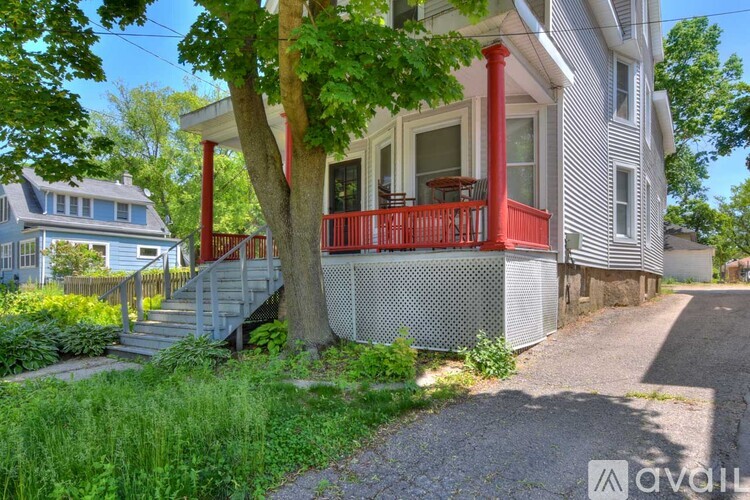 A house with a red balcony and a tree in front.