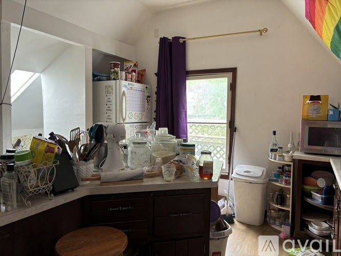 A kitchen with a lot of clutter on the counter and in the cupboards.