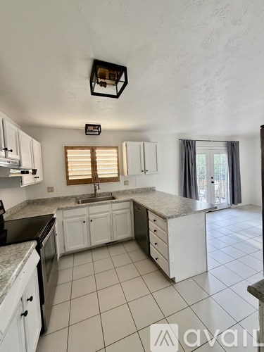 A kitchen with white cabinets and a black dishwasher.