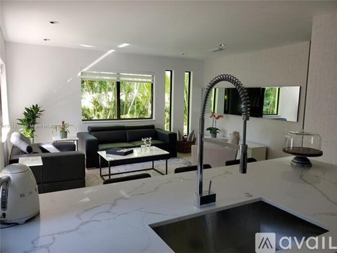 A modern kitchen with a marble countertop and a large window.