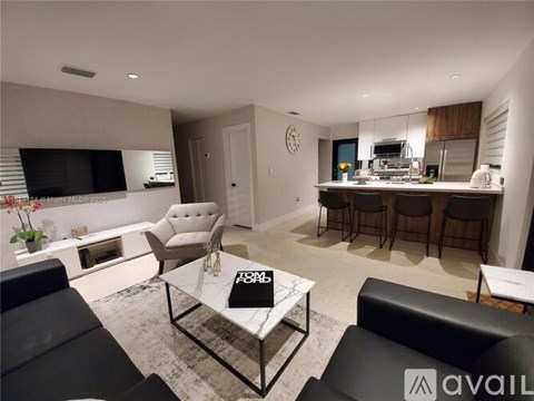A modern living room with a black leather couch and a glass coffee table.