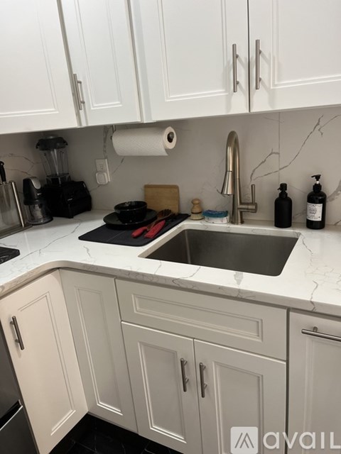 A kitchen with white cabinets and a marble countertop.