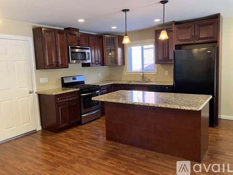 A kitchen with dark wood cabinets and a granite countertop.