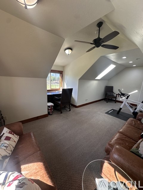 A living room with a brown leather couch and a ceiling fan.
