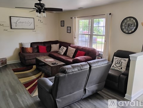 A living room with a grey couch and a red cushion.